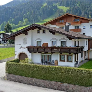 Ein stilvolles Haus in den Bergen mit einem gemütlichen Balkon. Umgeben von grünen Wiesen und majestätischen Bergen.