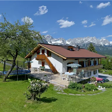 Ein schönes Haus in einer ruhigen Landschaft mit herrlichem Blick auf die Berge. Der Garten ist grün und enthält einen Spielplatz.