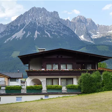Ein schönes Haus vor einer beeindruckenden Berglandschaft. Die Umgebung ist grün und einladend.