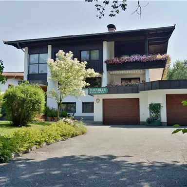 Ein modernes Haus mit zwei Garagen und blühenden Pflanzen. Der Eingangsbereich ist von einem gepflegten Garten umgeben.