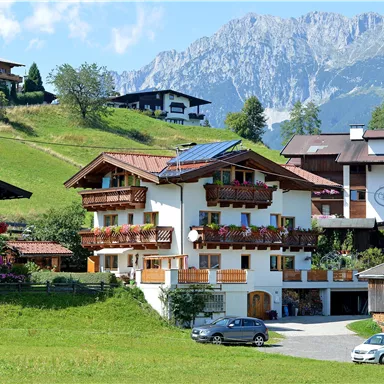 A picturesque village in the mountains with traditional houses and green meadows. In the background, tall mountains can be seen.