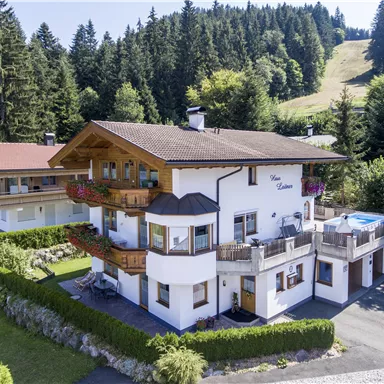 A charming house in Alpine style, surrounded by green forests and hills. It has a balcony and a pool in the garden.