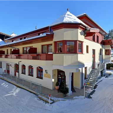 A charming building in winter with snow on the roof. Surrounded by snowy hills and blue sky.