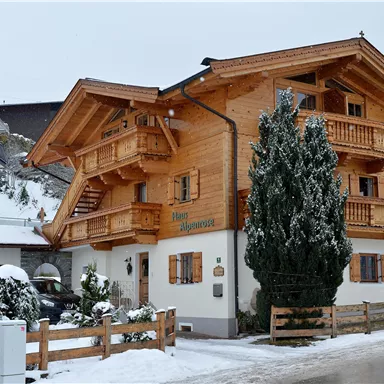 A charming wooden house in alpine style, surrounded by snow. The surroundings are calm and zen, ideal for a winter holiday.