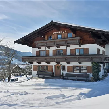 A picturesque house in alpine style, surrounded by snow-covered landscapes. The sky is clear and the mountains are visible in the background.