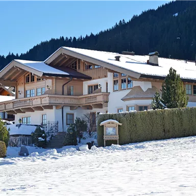 A beautiful, snow-covered building in the mountains. Surrounded by trees and a clear sky.