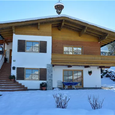 A beautiful house in Alpine style, surrounded by snow. The clear winter landscape gives the scene a cozy atmosphere.