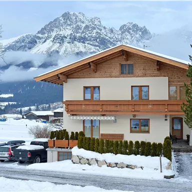 A beautiful house in the snow with a picturesque backdrop of mountains. The surroundings are calm and wintry.