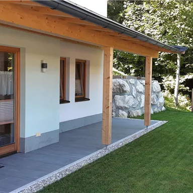 A modern house with a covered terrace. The well-kept garden and wooden fences create an inviting atmosphere.