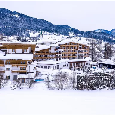 A picturesque winter village with snow-covered buildings and mountains in the background. The landscape is calm and inviting, perfect for a snow holiday.