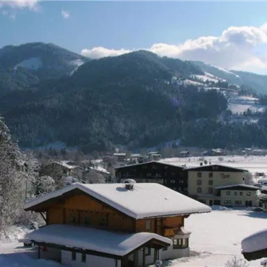 A beautiful winter landscape with snow-covered mountains and charming cottages. The clear sky and the snow create a peaceful atmosphere.