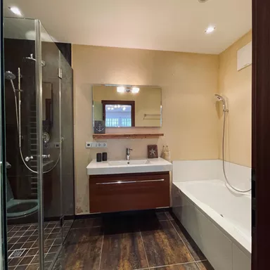 Ein modernes Badezimmer mit einer Dusche und einer Badewanne. Ein Spiegel und ein Holzschrank verleihen dem Raum eine elegante Note.