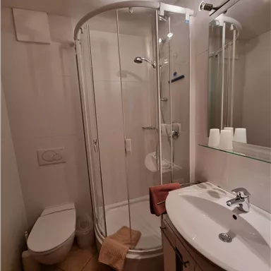 Ein modernes Badezimmer mit einer Duschkabine und einem Waschbecken. Das Raumdesign ist hell und funktional mit einer eleganten Ausstattung.