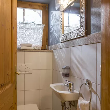 Ein modernes Badezimmer mit einer Dusche, Waschbecken und einem großen Spiegel. Die Wände sind hell gefliest, und ein Fenster sorgt für Tageslicht.