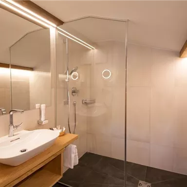 A modern bathroom with a glass shower and elegant sanitary fixtures. The lighting creates a cozy atmosphere.