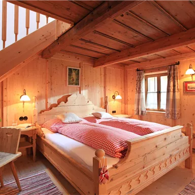 Ein gemütliches Schlafzimmer mit Holzwänden und einem großen Bett. Die warmen Lichter schaffen eine einladende Atmosphäre.