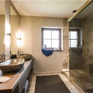 Ein modernes Badezimmer mit eleganten Armaturen und einem großzügigen Duschbereich. Große Fenster sorgen für viel Tageslicht und eine angenehme Atmosphäre.