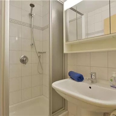 A modern bathroom with a shower and a sink. Towels and toiletries are neatly arranged.