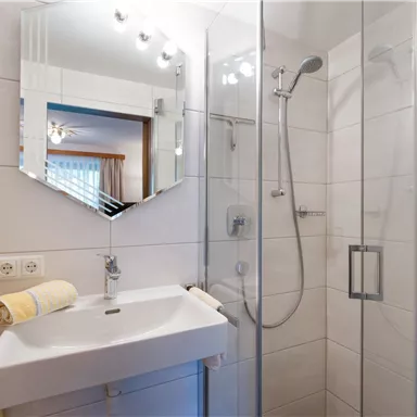 A modern bathroom with a glass shower and a sink. The walls are in neutral colors and there are soft towels.