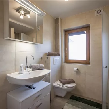 A modern bathroom with a bright color scheme. It has a sink, a shower, and a window.