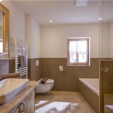 A modern bathroom with bright walls and a large bathtub. There is a sink and a large mirror.