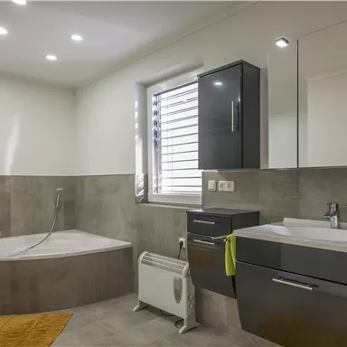 A modern bathroom with a bathtub and an elegant sink. The walls are light and the decor is stylish with decorative accents in yellow.
