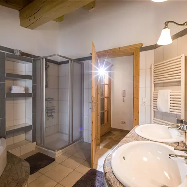 Ein modernes Badezimmer mit einer Dusche und einer Badewanne. Das stilvolle Design umfasst helle Fliesen und einen Holzrahmen.