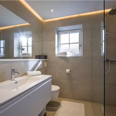 A modern bathroom with a stylish shower and a large mirror. Soft lighting and bright tiles create an inviting atmosphere.