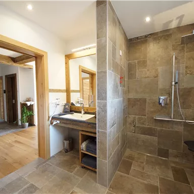 Ein modernes Badezimmer mit einer eleganten Dusche und stylischen Fliesen. Es gibt auch einen Waschbereich mit Holzdetails.