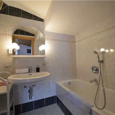 A modern bathroom with a bathtub and a sink. Bright tiles and a large mirror wall create a friendly atmosphere.