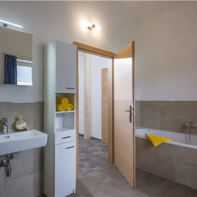 Ein modernes Badezimmer mit einer Badewanne und einem Waschbecken. Helle Farben und saubere Linien sorgen für eine einladende Atmosphäre.