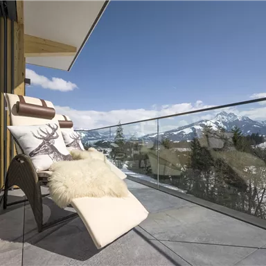 A cozy balcony with loungers and a view of snow-covered mountains. The blend of modern design and natural surroundings creates a relaxing atmosphere.