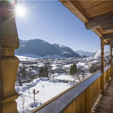 A sunny winter day with snow-covered mountains and a beautiful view from the balcony. The landscape is quiet and picturesque.