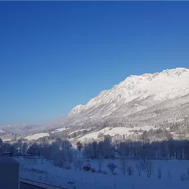 A snow-covered mountain landscape under a clear blue sky. The mountains are majestic and the scenery is calm and idyllic.