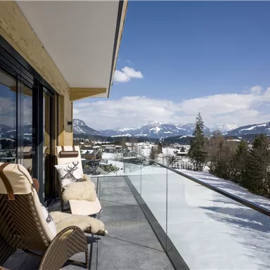 A cozy terrace with a view of the snow-covered mountains. The sky is clear and the landscape is picturesque.