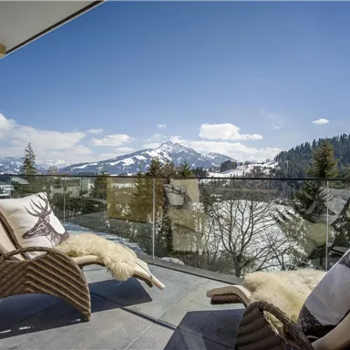 A stylish balcony with a view of snow-capped mountains and green trees. Relaxing loungers invite you to linger.
