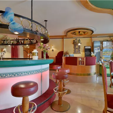 Eine gemütliche Bar mit einem runden Tresen und roten Stühlen. Die Einrichtung ist stilvoll und einladend.