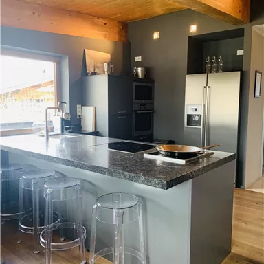 A modern kitchen with a large cooking island and clean lines. The wooden ceilings give the room a warm atmosphere.