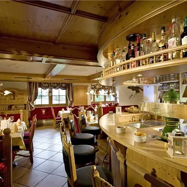 A cozy restaurant with wooden interiors and an inviting bar area. The tables are elegantly set, creating a warm atmosphere.