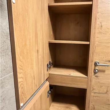 A wooden cabinet with several shelves and a door. The shelves are empty and provide plenty of storage space.