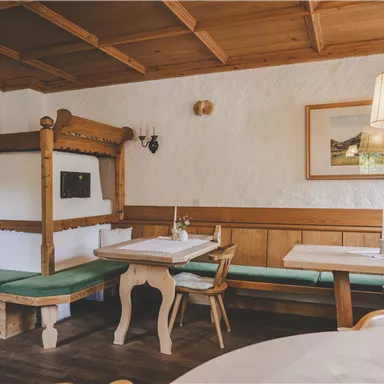 Gemütliches Restaurant mit Holzdekor und traditionellen Sitzbänken. Ein Tisch mit Blumenarrangement lädt zum Verweilen ein.