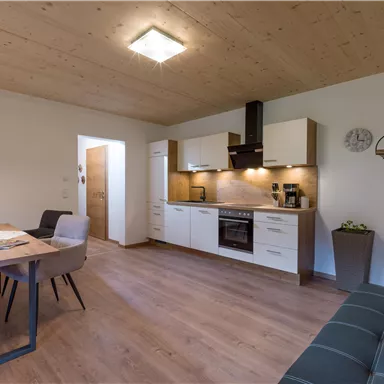 Eine moderne Küche mit einem Essbereich. Der Raum hat helle Wände und Holzverkleidung, was eine einladende Atmosphäre schafft.