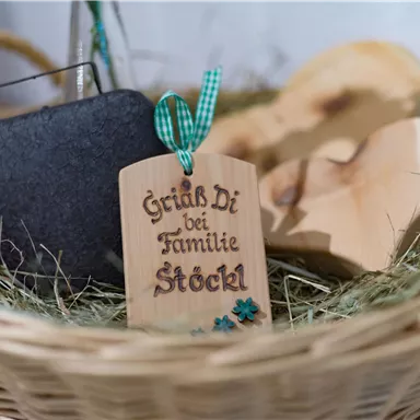 Ein Korb mit einer Holztafel, die "Grüß Di bei Familie Stöckl" sagt. Daneben liegen ein Stein und einige Holzformen.