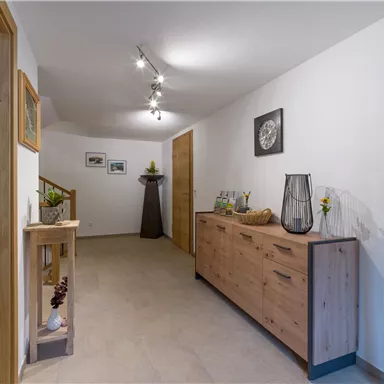 A modern hallway with wooden shelves and a stylish floor lamp. The walls are painted light and there are some decorative elements.