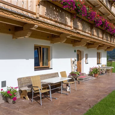 A charming house with wooden cladding and colorful flower boxes. The outdoor area provides seating on a terrace overlooking nature.