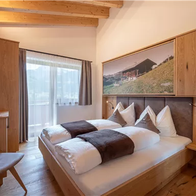 Ein gemütliches Schlafzimmer mit zwei Betten und Holzdetails. Das Zimmer hat einen Balkon und einen Fernseher.
