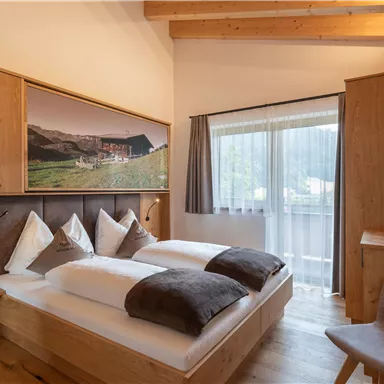 Ein gemütliches Schlafzimmer mit Holzverkleidung und einem großen Fenster. Zwei Betten mit bequemen Kissen und ein modernes Dekor schaffen eine einladende Atmosphäre.