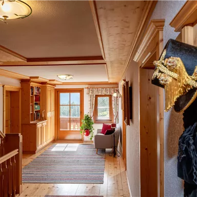 Ein einladender Flur mit Holzverkleidung und einer Treppe. Im Hintergrund sieht man ein großes Fenster mit Blick auf die Landschaft.