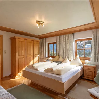 Ein gemütliches Schlafzimmer mit Holzdetails und zwei Einzelbetten. Es gibt Fenster mit Blick auf die Berge und eine entspannte Atmosphäre.