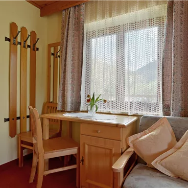 Ein gemütlicher Wohnbereich mit einem Tisch, Stühlen und einem Sofa. Das Fenster lässt viel Licht herein und bringt eine einladende Atmosphäre.